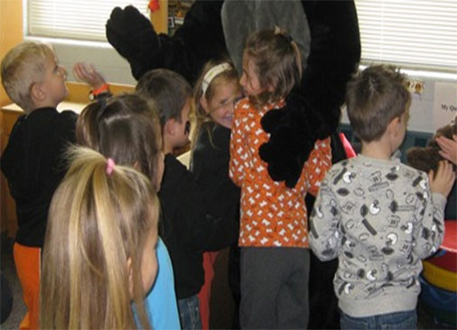 Kids hugging a person in a black cat suit