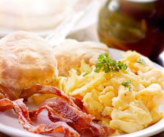 A close up view of a plate of biscuits, eggs, and crispy bacon